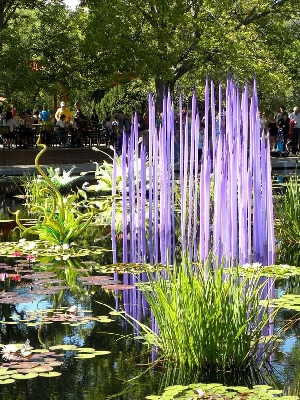 Denver Botanic Gardens with Purple glass art by a lily pond under green trees near Warwick Denver