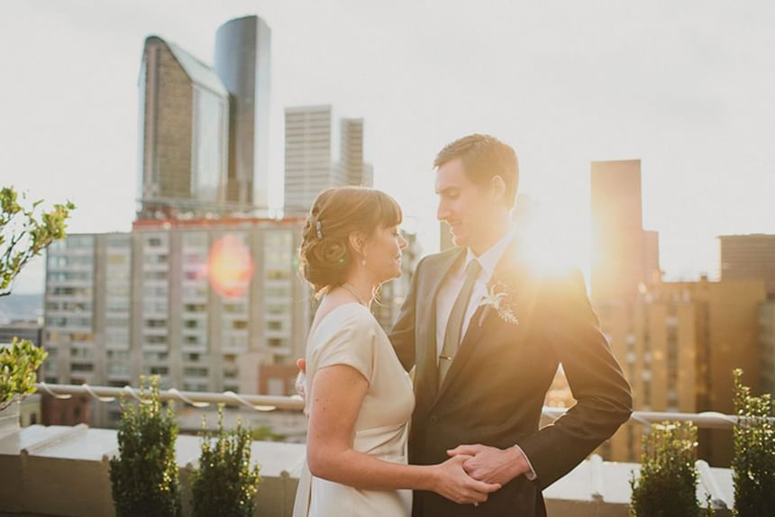 Couple posing on a rooftop at sunset, with a city skyline backdrop in Hotel Sorrento