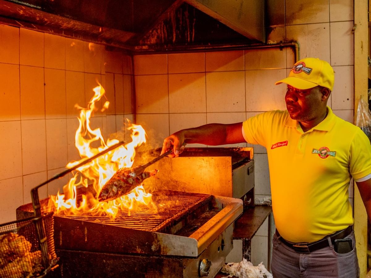 Chef flipping grilled fish over open flames, highlighting top restaurants in Kingston at Jamaica Pegasus Hotel