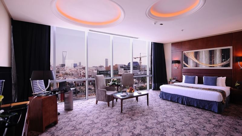 Bed & lounge area with a city view in Junior Suite at Al Hamra Palace by Warwick Riyadhd