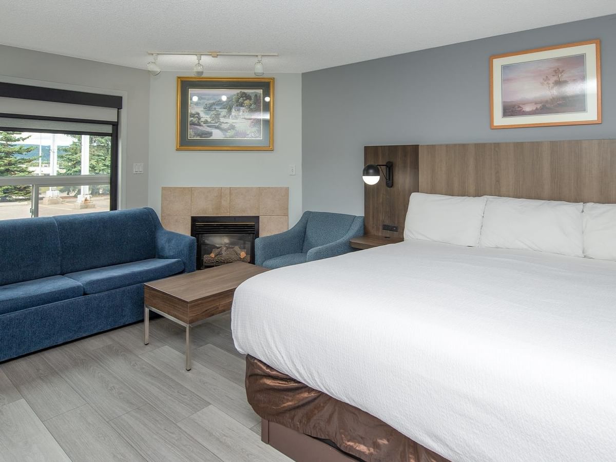Coast Premium King Suite with king bed, blue sofa, fireplace and wood accents.