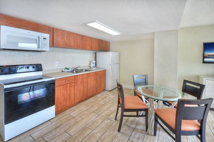 A kitchen with appliances, cabinets, and a dining area with a table and chairs.