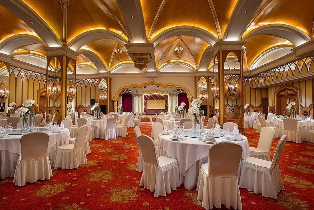 Celebrity Banquet Room with  banquets under arched gold ceilings & red floral carpet at Celebrity International Grand Hotel