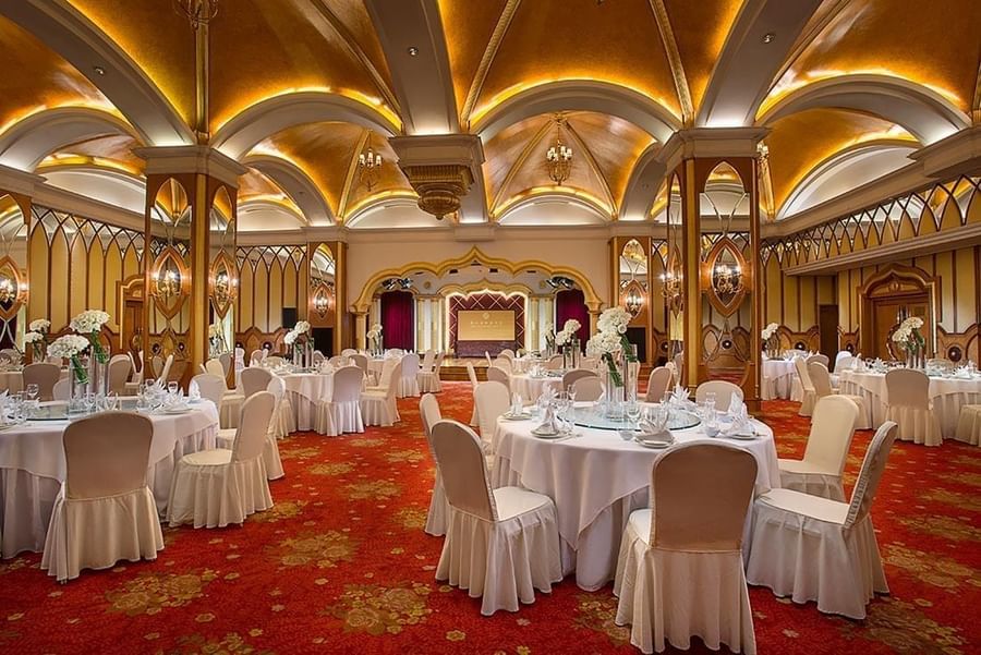 Celebrity Banquet Room with  banquets under arched gold ceilings & red floral carpet at Celebrity International Grand Hotel