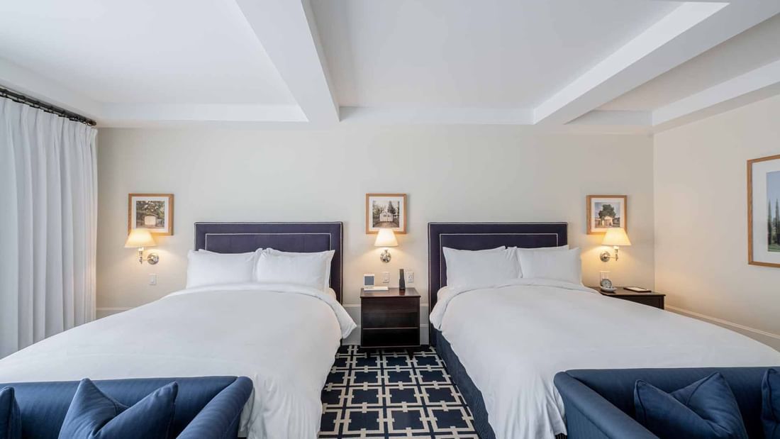 Deluxe Queen Queen with cozy beds, blue headboards, and plush seating at El Prado Hotel