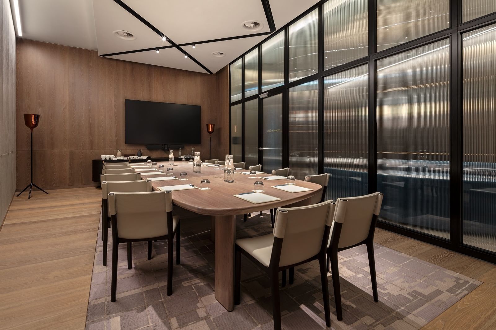 Serpentine Gallery meeting room at The Londoner Hotel, set with a large table, modern chairs, and a wall-mounted TV