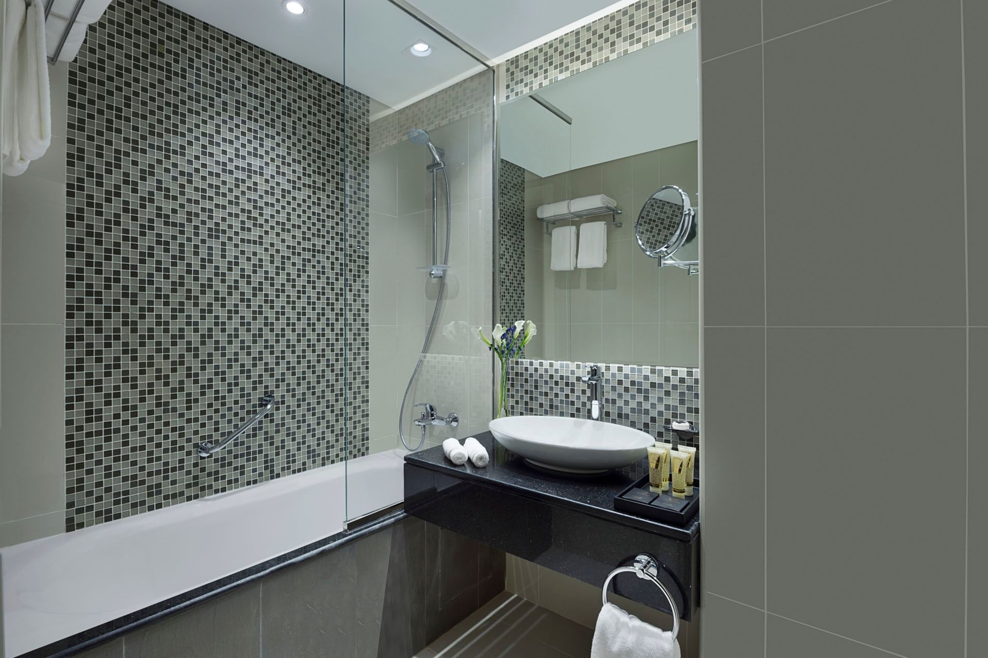Bathtub and vanity with toiletries amenities in Studio Bathroom at DAMAC Maison Distinction