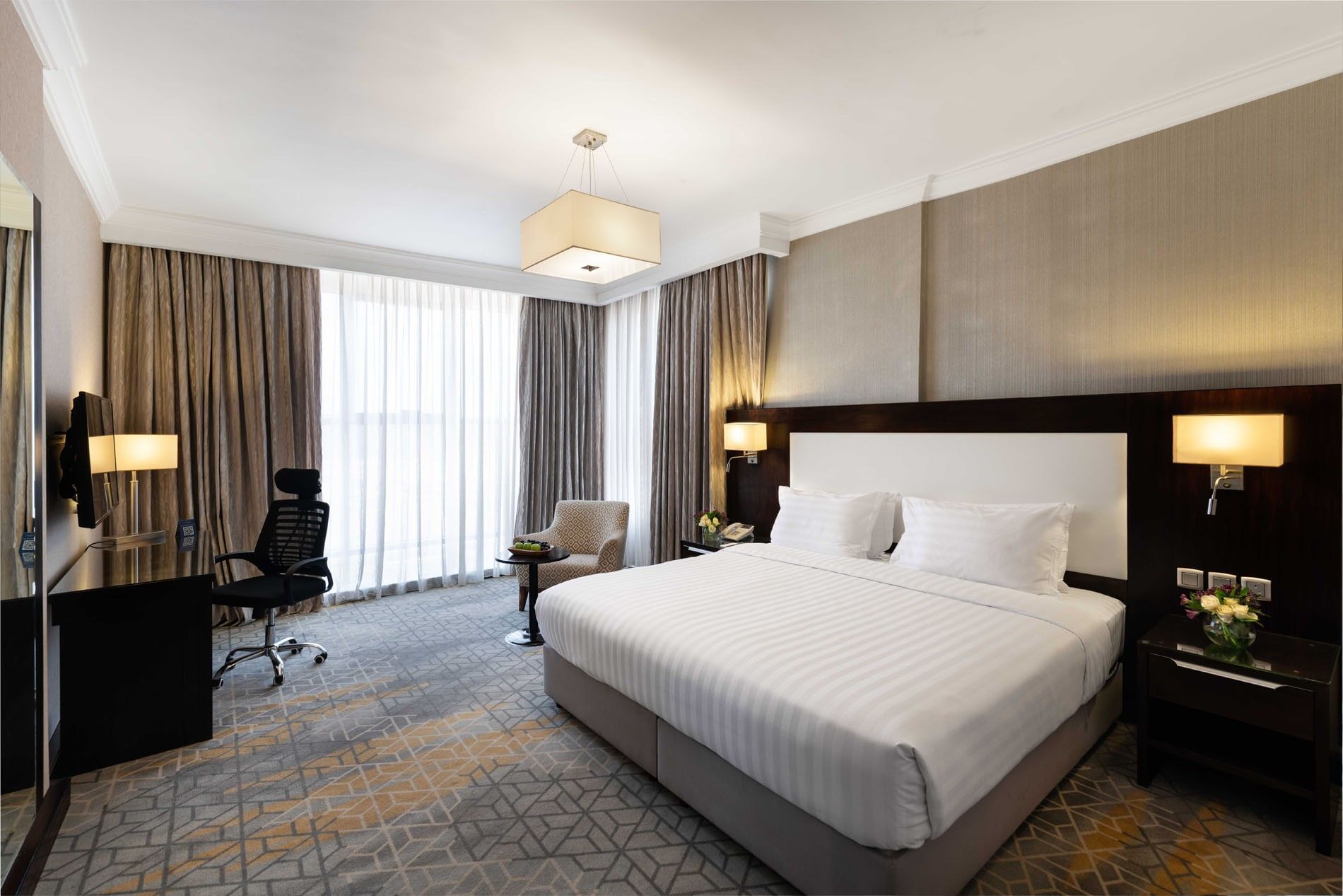 Wall-mounted TV, nightstands, and a work desk by the cozy bed in the Superior Room at Warwick Hotel Jeddah