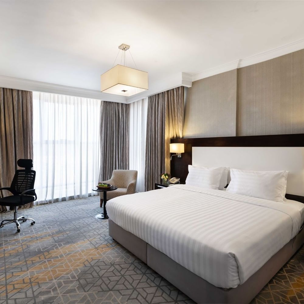 Wall-mounted TV, nightstands, and a work desk by the cozy bed in the Superior Room at Warwick Hotel Jeddah