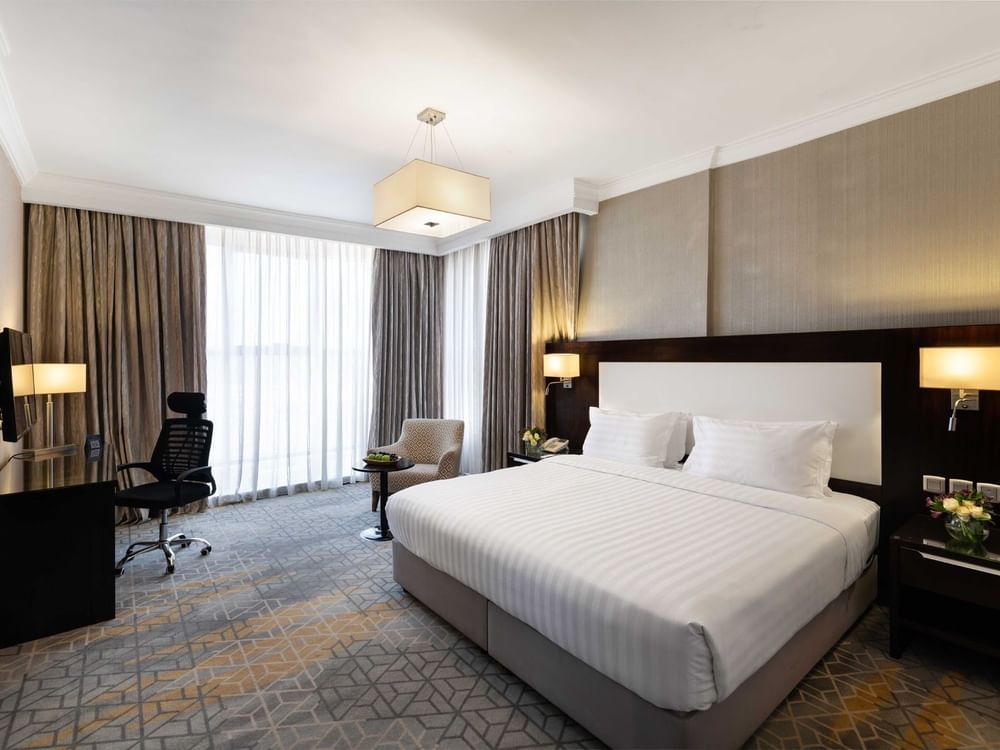 Wall-mounted TV, nightstands, and a work desk by the cozy bed in the Superior Room at Warwick Hotel Jeddah