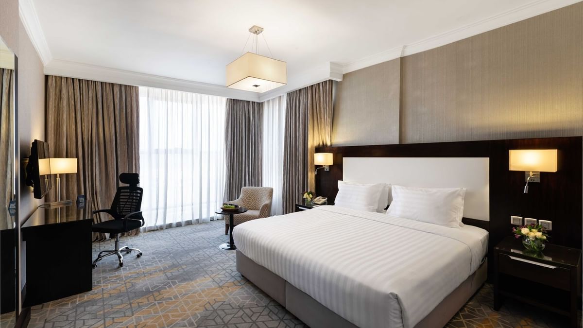 Wall-mounted TV, nightstands, and a work desk by the cozy bed in the Superior Room at Warwick Hotel Jeddah