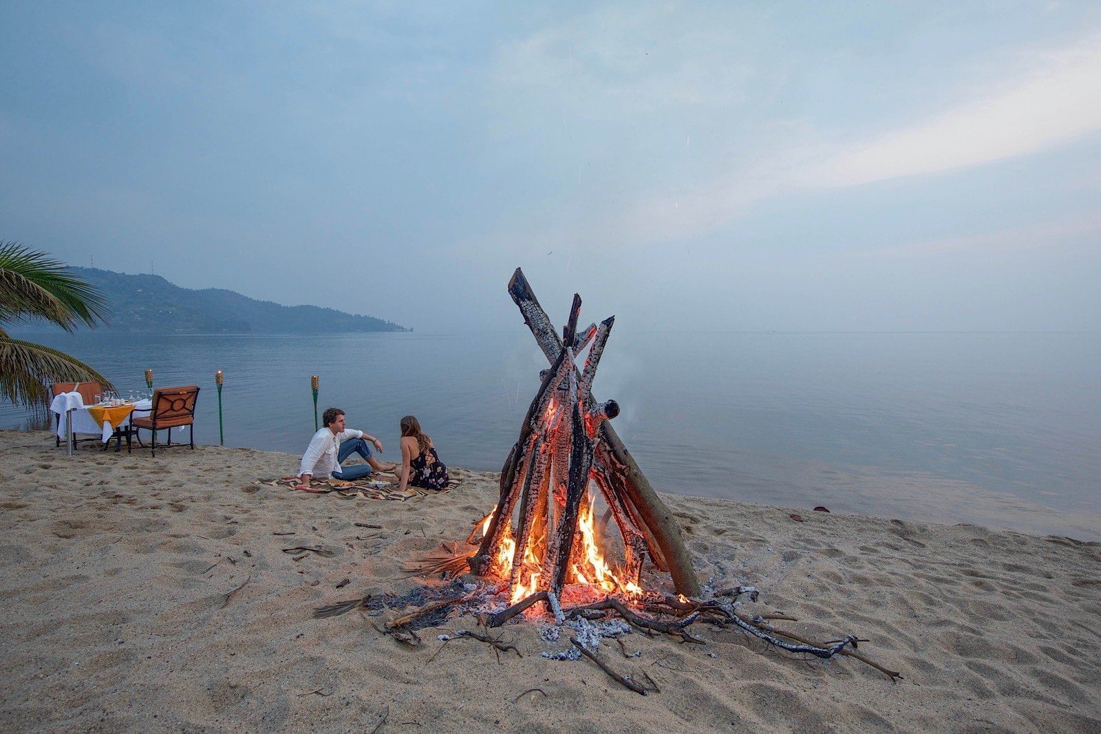 Couple near a bonfire by the lake at Lake Kivu Serena Hotel