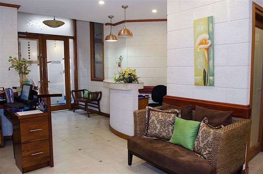Woven sofa with green pillows by a curved reception desk in the Chakra Spa at Accra Beach Hotel & Spa