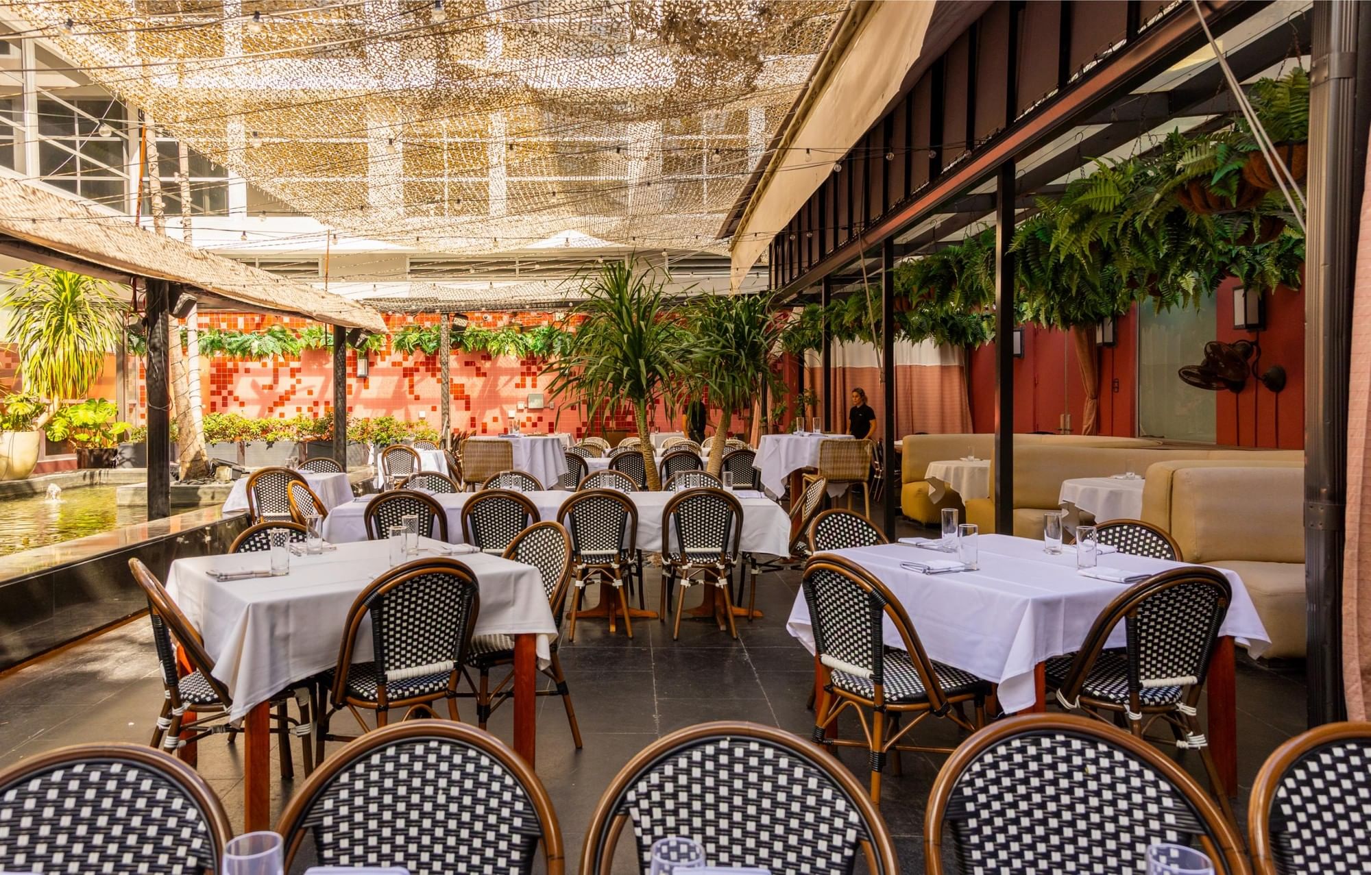 A covered outdoor dining area with white tablecloths and plants