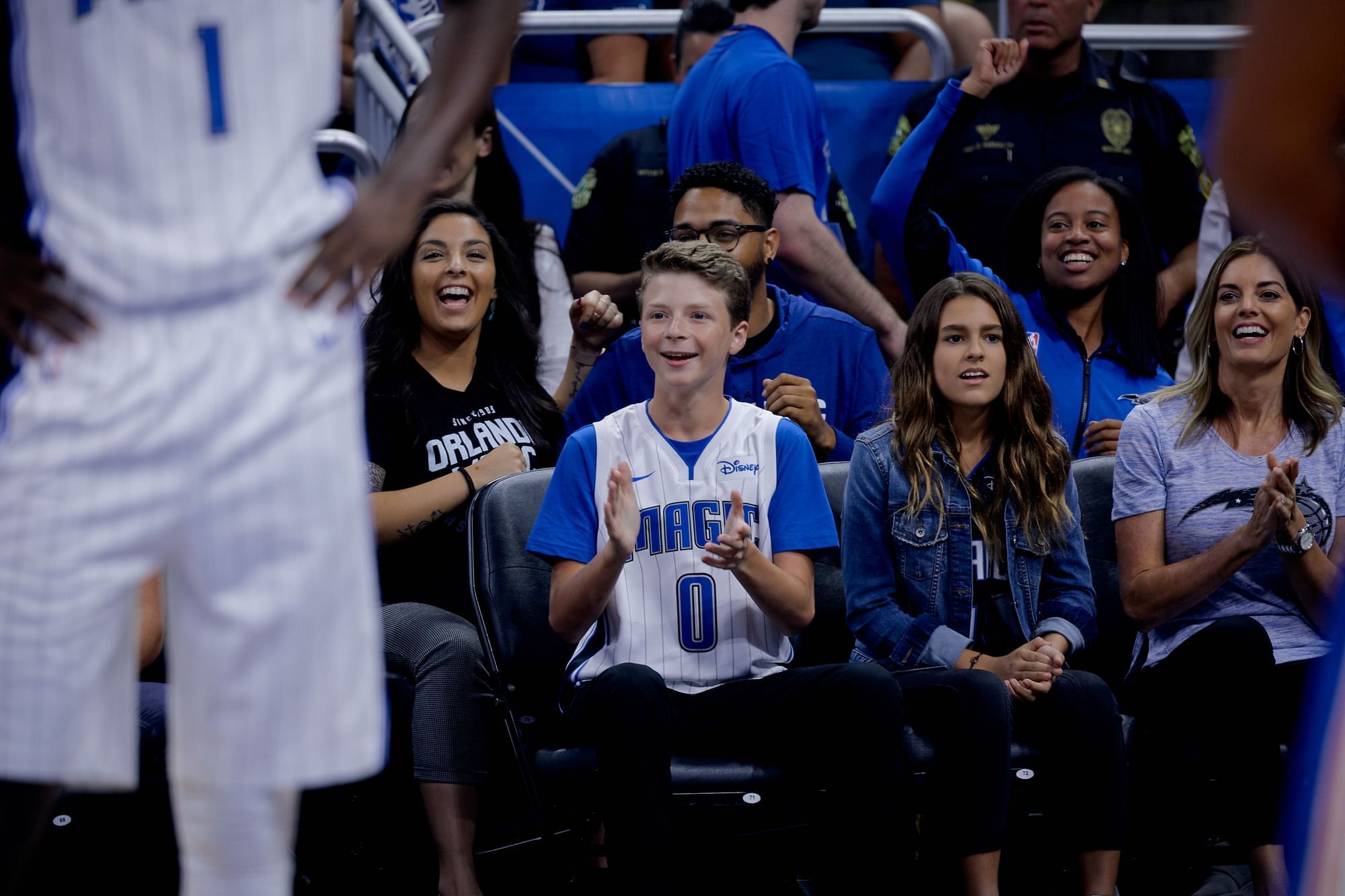 Several fans in Orlando Magic gear applaud from their seats next to the court.