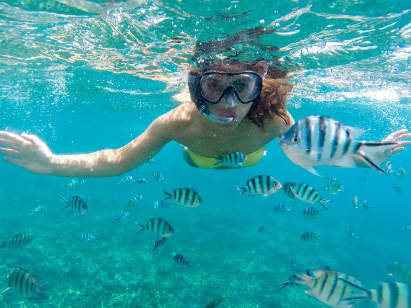 A lady in a snorkel mask and goggles enjoying a swim in the sea near Hotel Isla Del Encanto