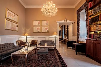 Elegant lounge with chandelier, furniture, and bookshelves at Kokkedal Slot Copenhagen by Warwick