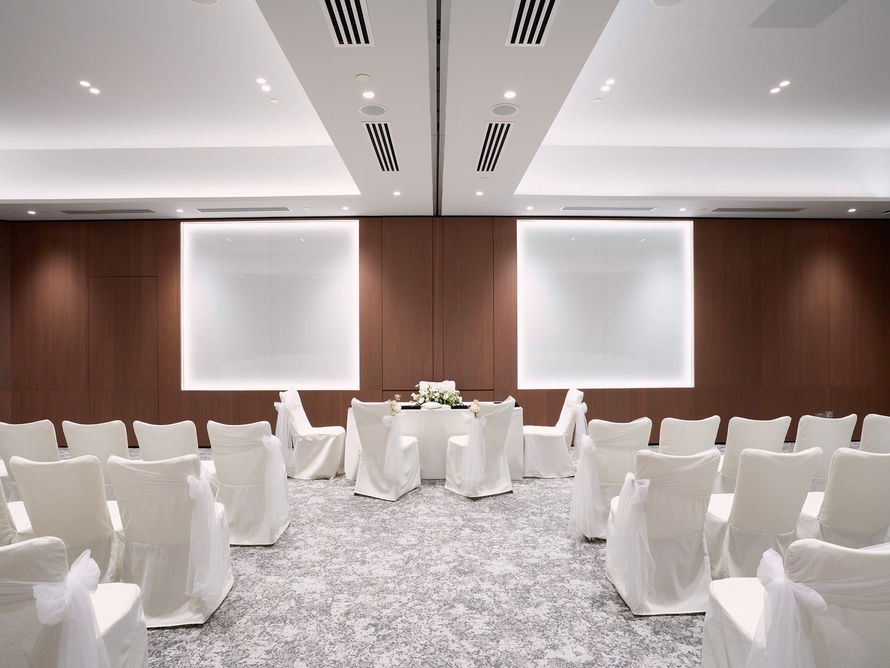 Solemnisation setup in a meeting room at Paradox Singapore, featuring an elegant arrangement with a decorated ceremonial table, chairs for guests, and tasteful floral accents in a bright, intimate setting.