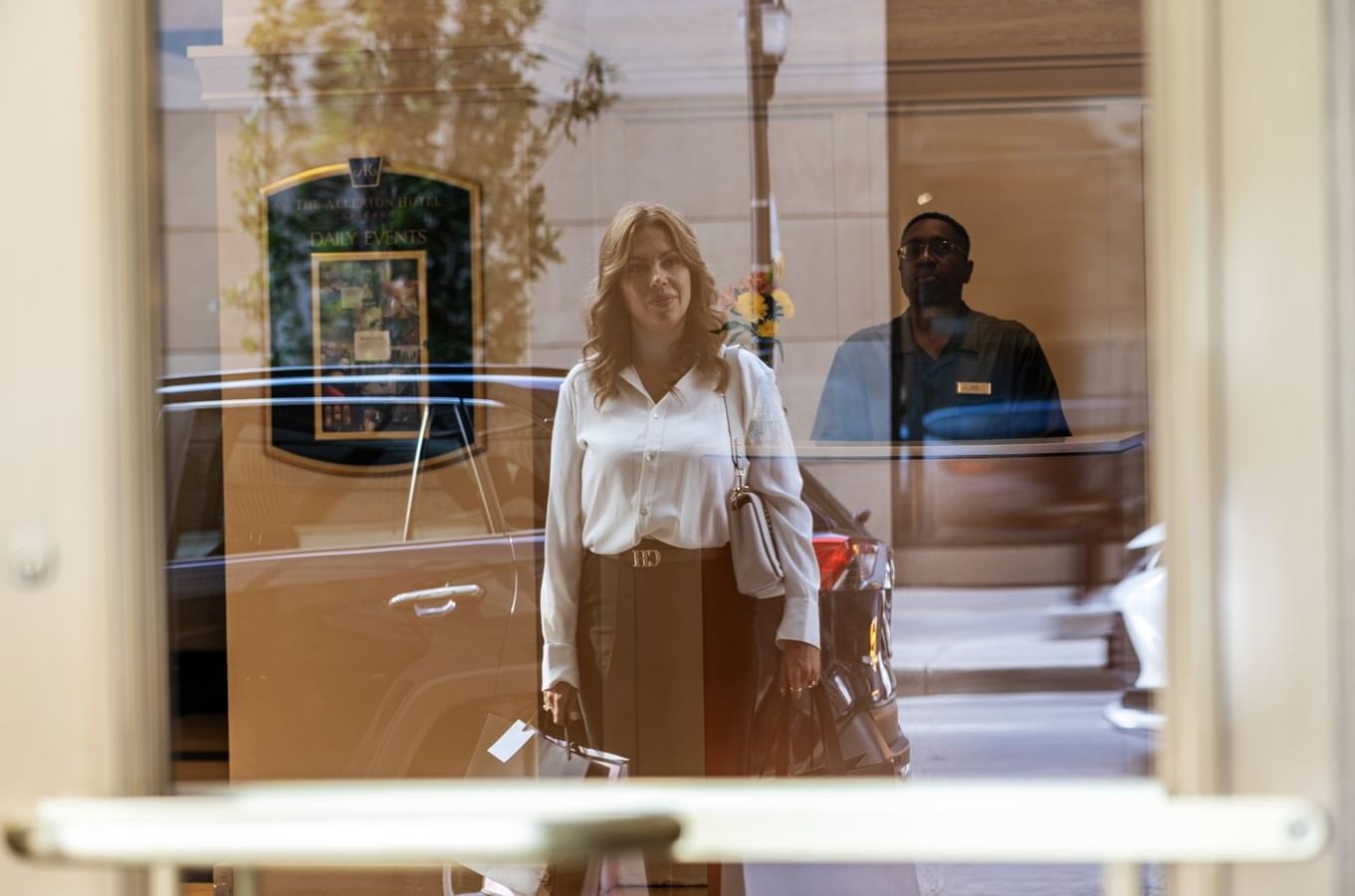 Woman standing outside a window, reflected by the glass near the entrance of the Warwick Allerton Chicago