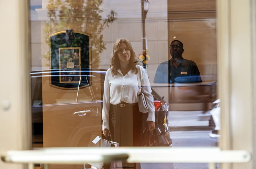 Woman standing outside a window, reflected by the glass near the entrance of the Warwick Allerton Chicago