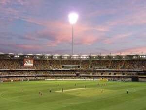 The Gabba cricket field with players and floodlights illuminating the pitch under a colourful sunset near The Sebel Brisbane