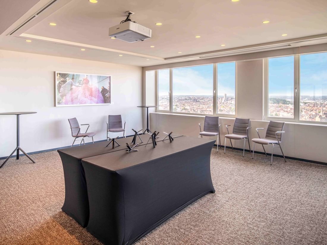 Meet 25 Three conference room with city view, a projector, chairs, and a large table at The Hotel Brussels