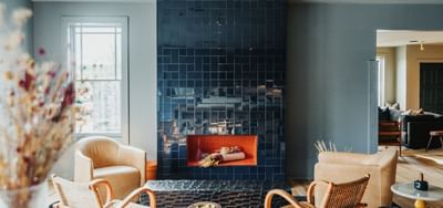 Living room with navy blue tiled fireplace and tan armchairs at The Stonebreaker Hotel