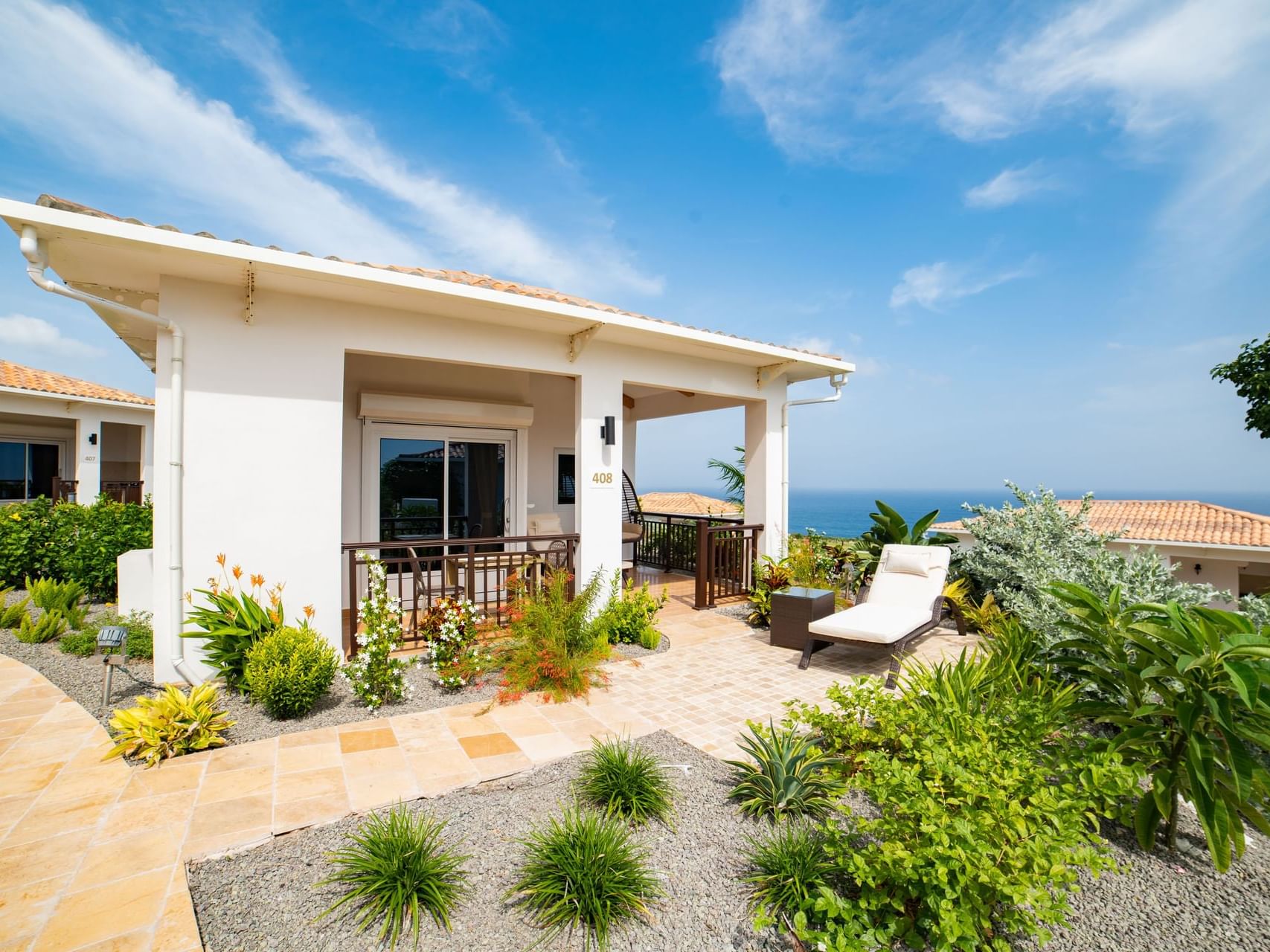 Exterior view of One-Bedroom Cottage with lush gardens, featuring a private patio and lounge chair at Golden Rock Resort