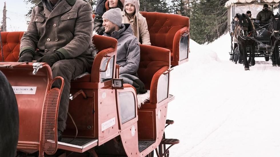 A family on a sleigh ride near Falkensteiner Hotels