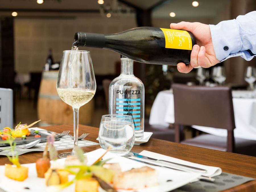 A waiter pouring wine at Hotel & SPA du Domaine des Thomeaux