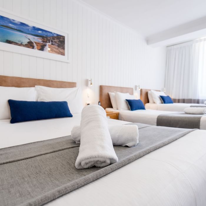 Clean hotel room with white linens, gray throw, and two rolled towels at Mercure Charlestown.