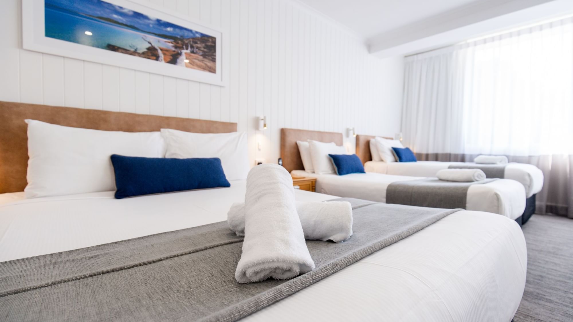 Clean hotel room with white linens, gray throw, and two rolled towels at Mercure Charlestown.