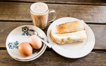 A breakfast setup with toast, boiled eggs and a latte on a wooden table at Park Hotel Group