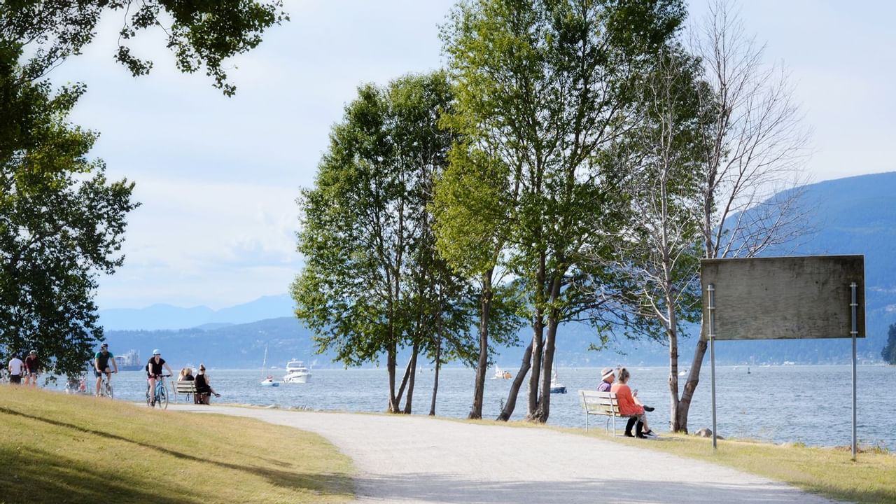 Bikers and walkers in Stanley Park with a river view near Midnight Sun, a Coast Hotel