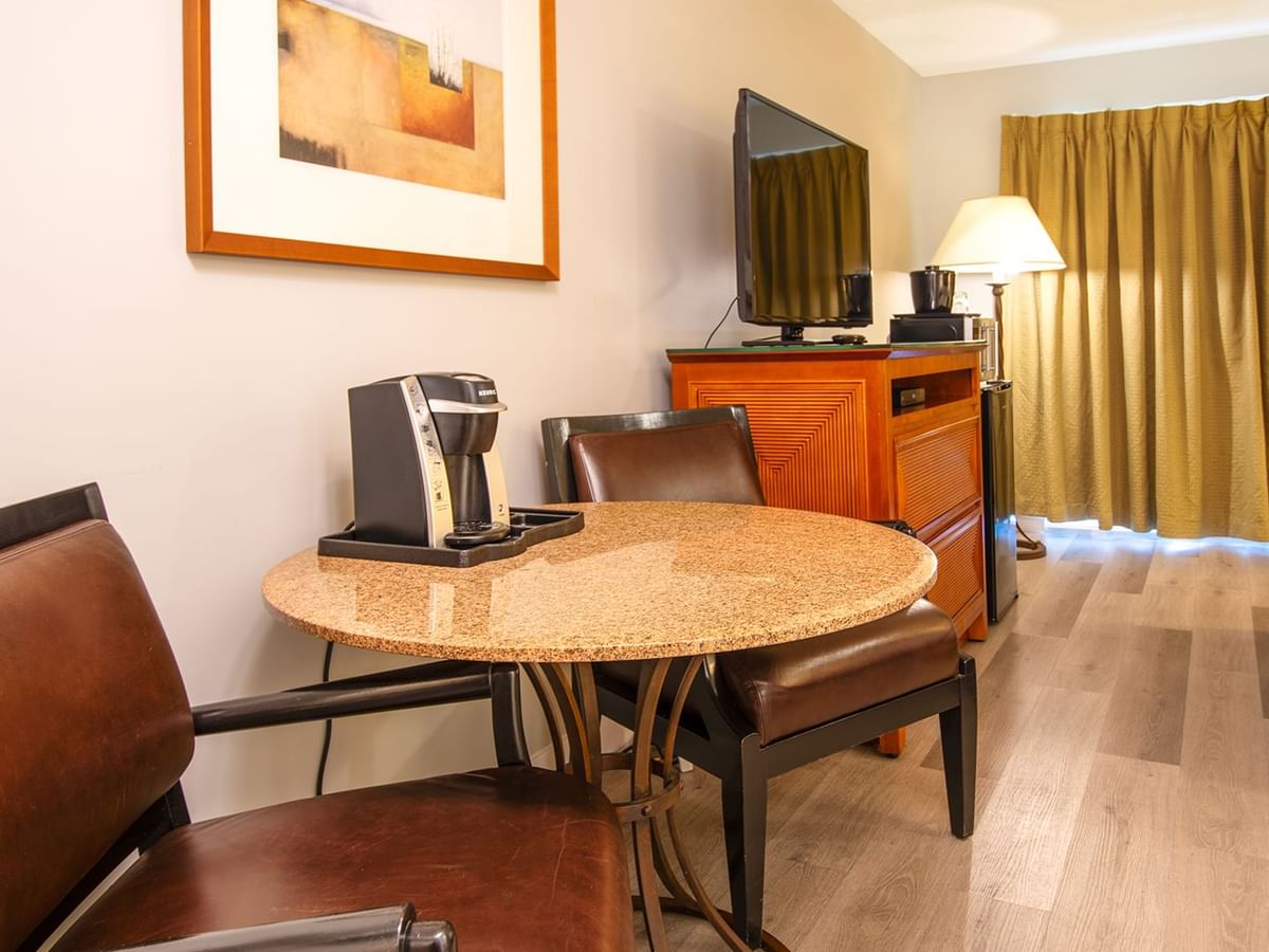 Hotel guestroom with queen bed, TV, table and coffee machine