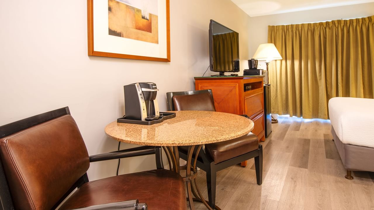 Hotel guestroom with queen bed, TV, table and coffee machine