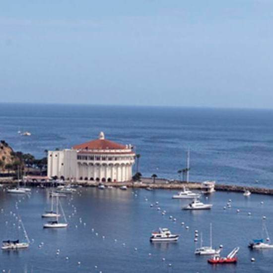 Oceanfront building with boats anchored nearby against a sea backdrop near Catalina Island Company