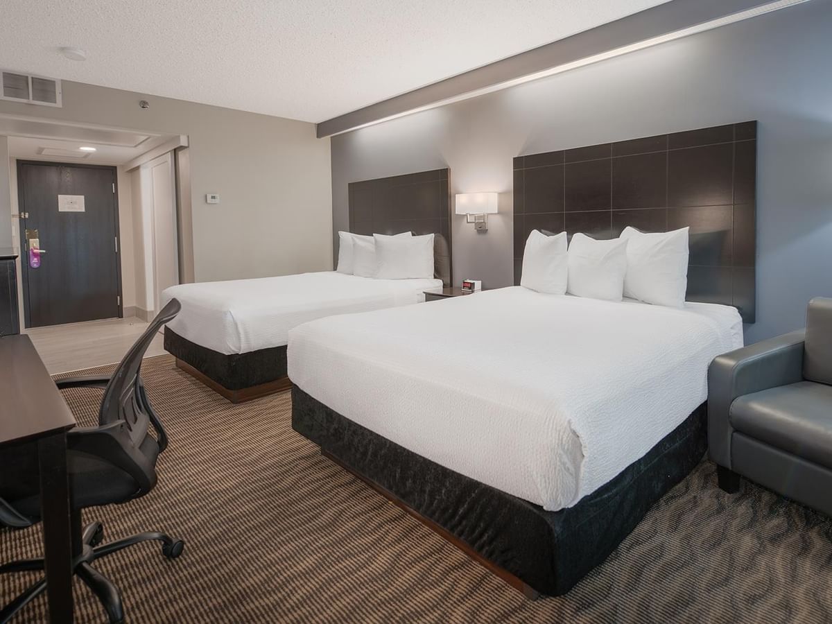 Two queen beds, a desk, chair, and armchair.