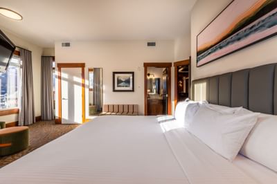 King-size bed with cushioned headboard and loungers in the Four Bedroom Penthouse Suite at Blackstone Mountain Lodge