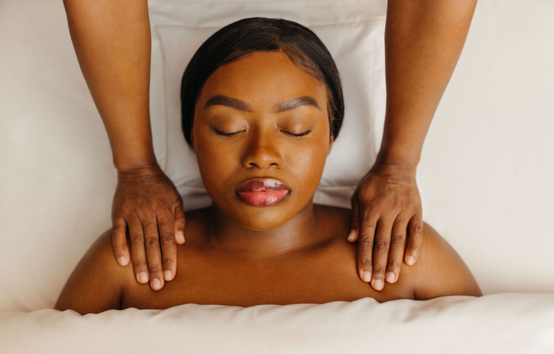 Woman receiving a relaxing shoulder massage with therapist hands resting on shoulders at Guerlain Spa at Hotel X Toronto