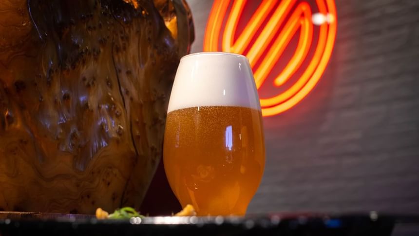 Cold craft beer with frothy foam in a tulip glass beside a wooden vase at the Media Sangre inside Araiza Calafiano