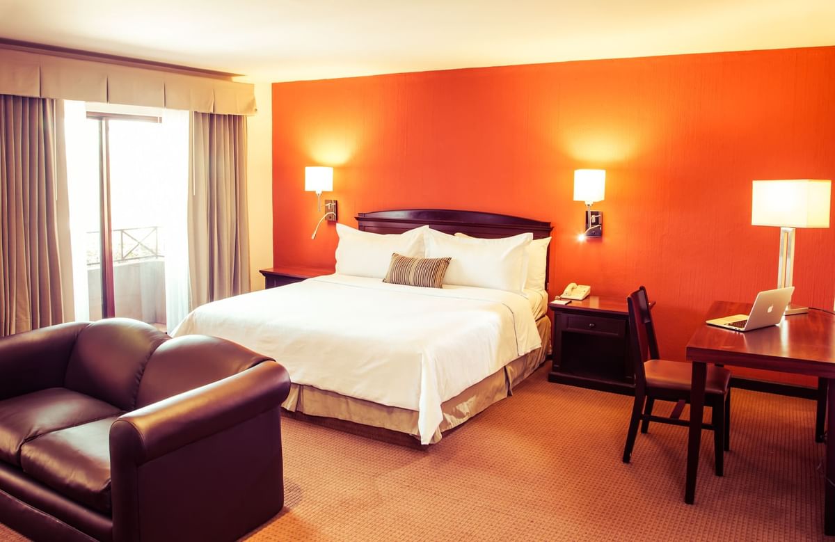 Interior de una espaciosa suite junior con una cómoda cama y área de trabajo en Gamma Hotels