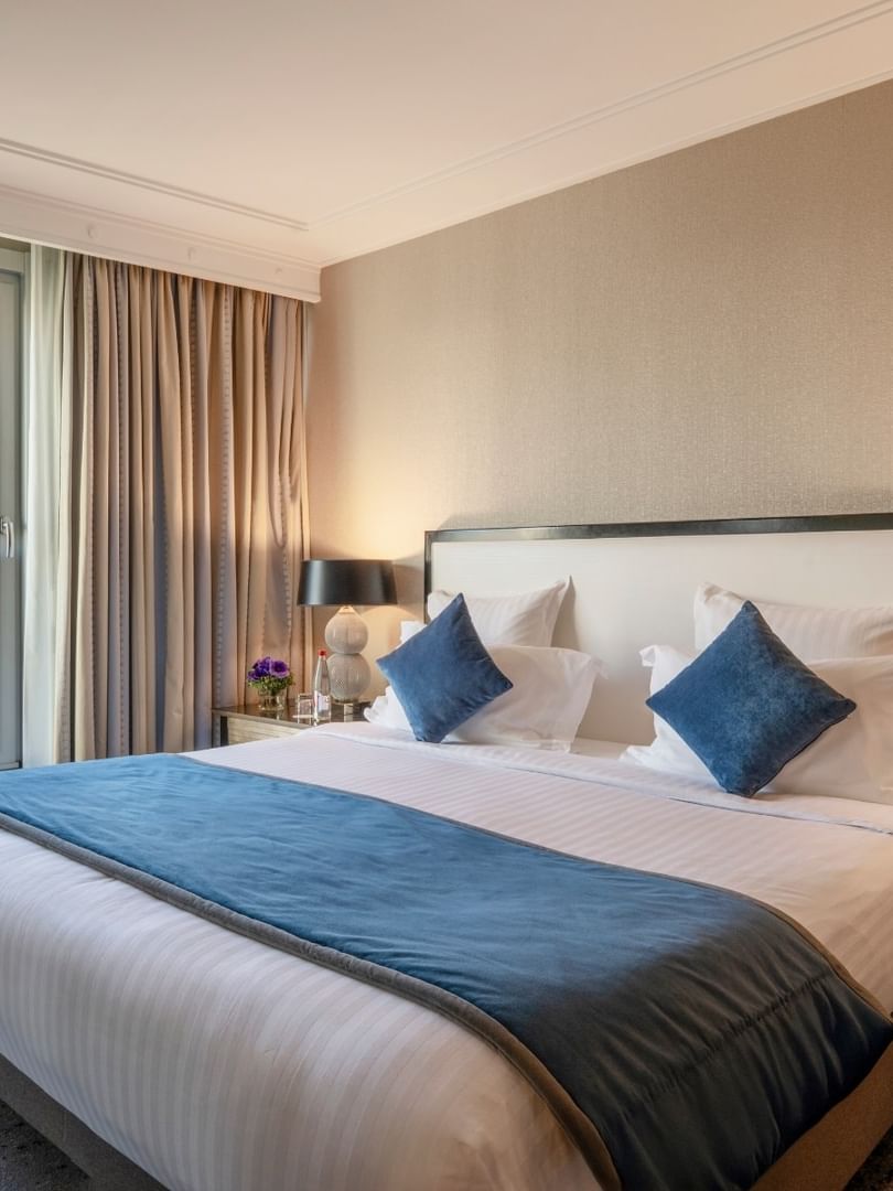 Neat bed with blue pillows by silver ball lamps in The Champs-Élysées Suite at Warwick Paris Champs Elysées