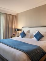 Neat bed with blue pillows by silver ball lamps in The Champs-Élysées Suite at Warwick Paris Champs Elysées