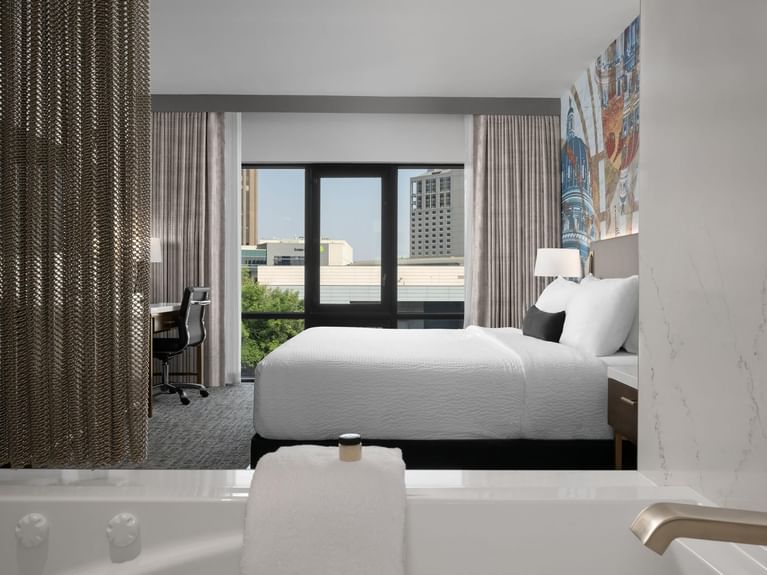 Capitol Parlor Suite with a large bed, an ornate mural, a desk, and a bathtub visible from the room at Hotel 43 Boise