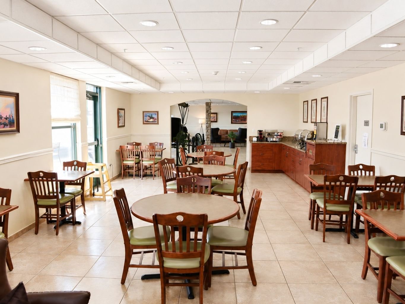 Bright breakfast dining area with wooden tables and chairs and buffet station at Booking - Boothill Inn