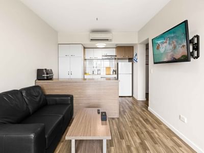 Black leather couch and TV in UniLodge Darwin's modern living space.