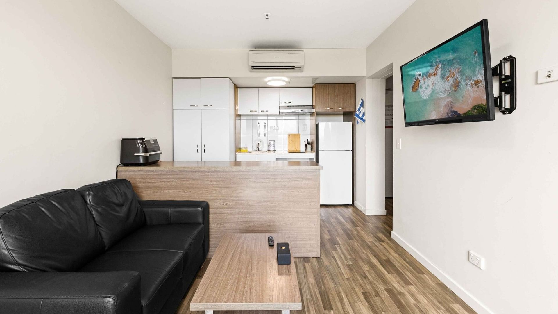 Black leather couch and TV in UniLodge Darwin's modern living space.