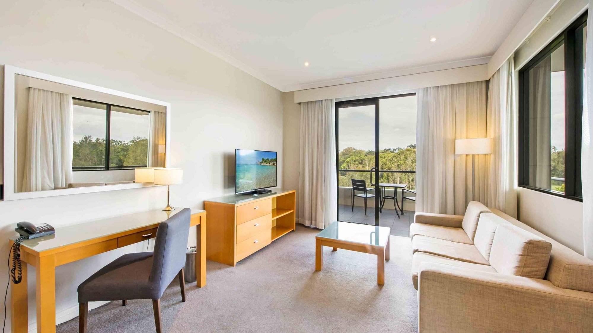 Privilege Room with sofa, desk, TV, and balcony overlooking greenery at Mercure Kooindah Waters