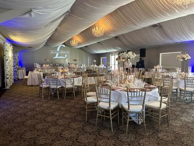 Grand Pavilion with white drapes, chandeliers, and floral centerpieces at Lake Natoma Inn